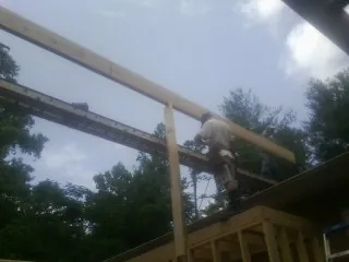 Carpenter setting a ridge beam over a new addition frame — Ice Dam Removal by Roofing Brothers in Park Valley