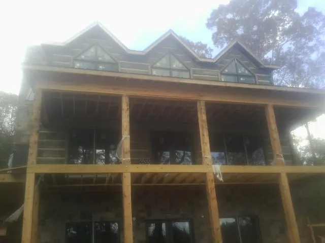 Dormers and porch framing on a large log home under construction — Roof Coating work by our crew in Park Valley