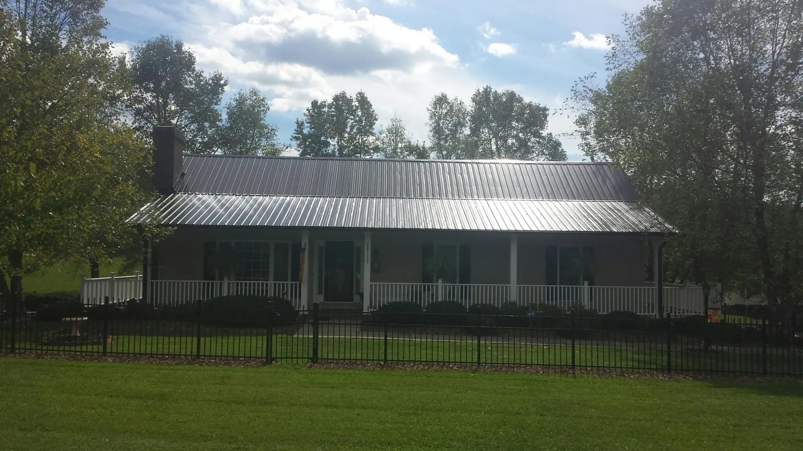 Gray metal roof on a brick ranch with a full width front porch — Gutter Guard Installation work by our crew in Park Valley