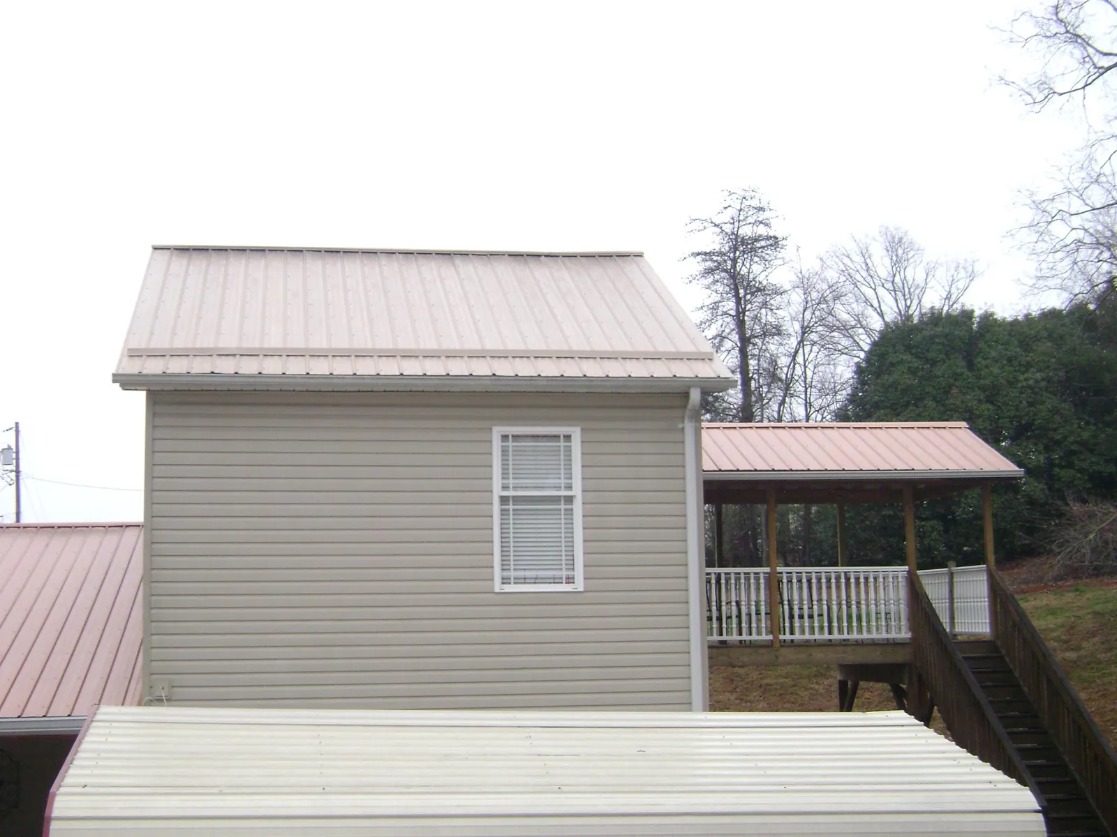 Tan metal roofs on a two story addition and attached porch, from a Roof Replacement job in Park Valley