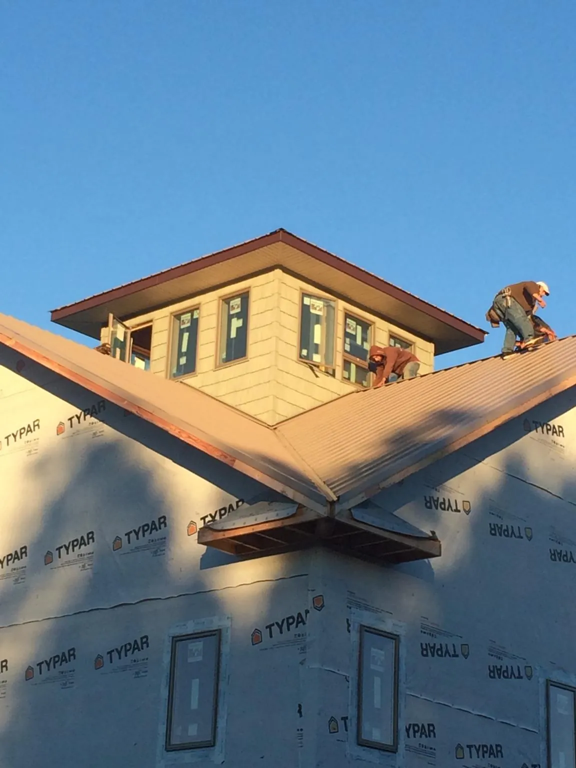Roofers working around a rooftop cupola on a new metal roof at sunset — Roof Waterproofing in Park Valley by Roofing Brothers